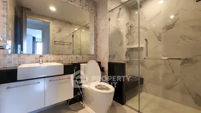 Modern bathroom with glass shower, sleek sink, and large mirror in a stylish apartment.
