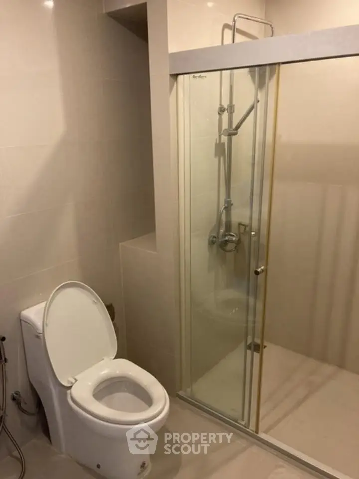 Modern bathroom with glass shower enclosure and sleek toilet design.