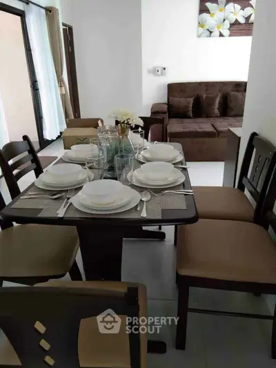 Elegant dining area with modern table setting and cozy living room in open layout apartment.