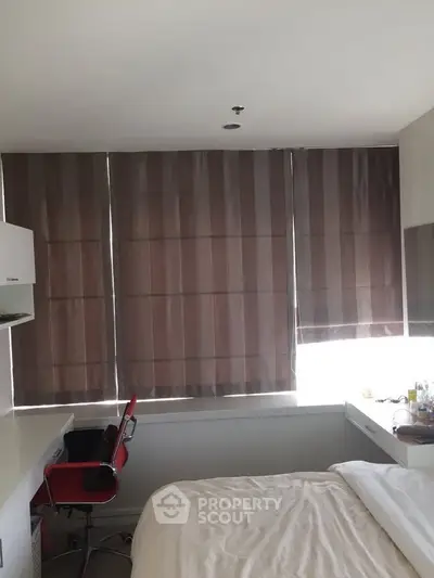 Cozy bedroom with modern furnishings and large windows with blinds, ideal for relaxation and comfort.