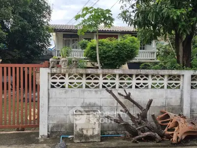 Charming suburban house with lush greenery and unique garden sculptures.