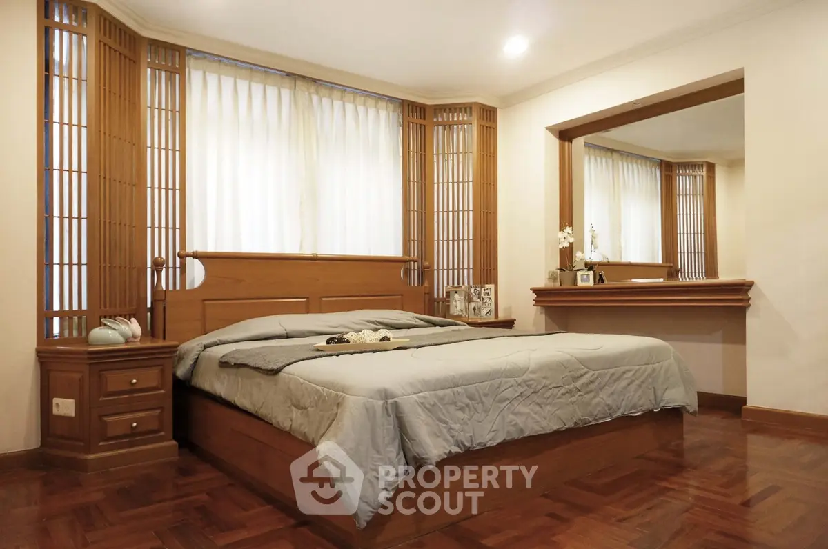 Elegant bedroom with wooden accents and large mirror, perfect for relaxation.