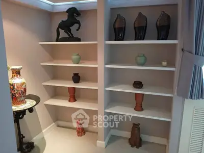 Elegant built-in shelves with decorative vases and sculptures in a stylish living room corner.