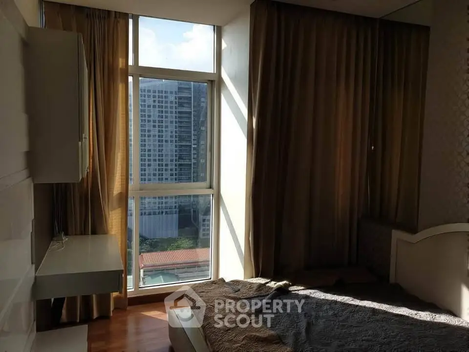 Spacious bedroom with large window offering stunning city view and natural light.