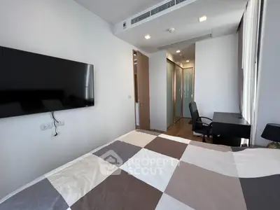 Modern bedroom with wall-mounted TV and sleek workspace in a stylish apartment.