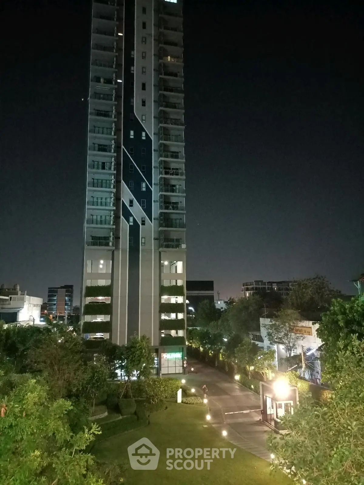 Stunning night view of a modern high-rise building with lush garden landscape.