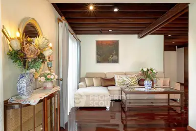 Elegant living room with plush sofa and floral decor, showcasing polished wooden floors and cozy ambiance.
