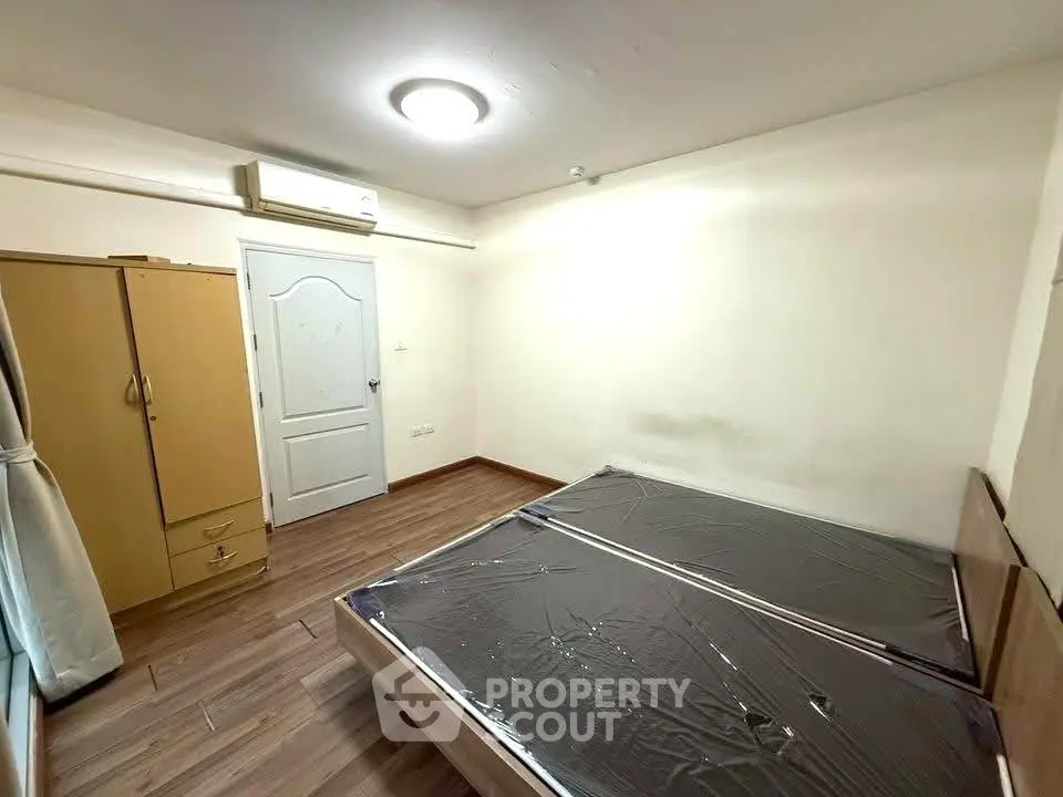 Spacious bedroom with wooden flooring and ample natural light, featuring a wardrobe and air conditioning.