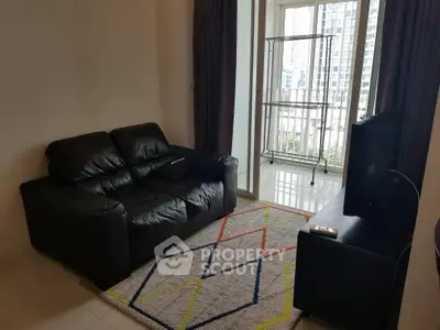 Cozy living room with black leather sofa and modern TV setup in a high-rise apartment.