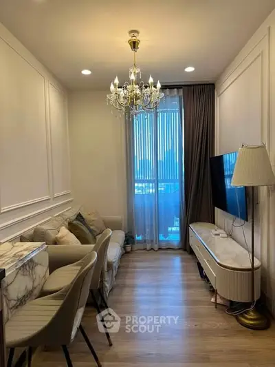 Elegant living room with chandelier, modern furniture, and large window for natural light.