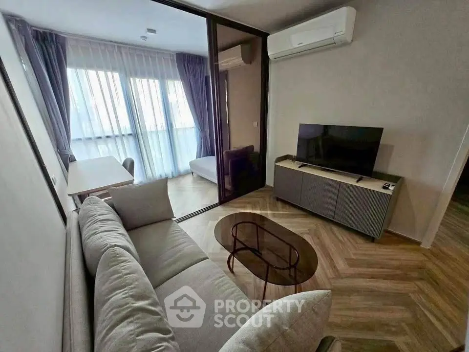 Modern living room with stylish furniture and large window, featuring air conditioning and a sleek TV setup.