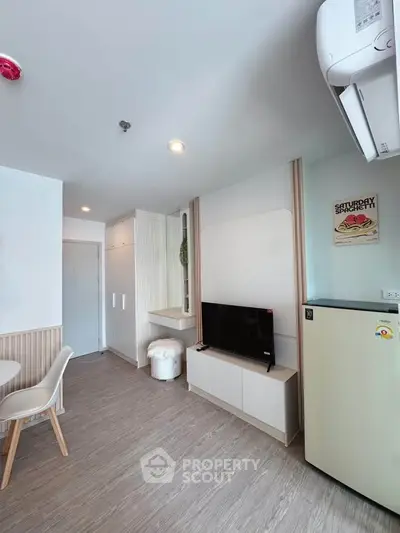 Modern living room with sleek design, featuring a TV, air conditioning, and stylish furniture.