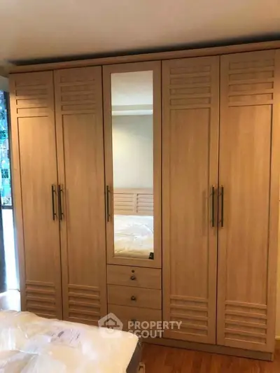 Spacious wooden wardrobe with mirror in a cozy bedroom setting.