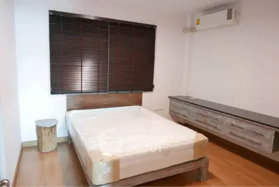 Modern bedroom with wooden furniture and air conditioning, featuring a comfortable bed and stylish decor.