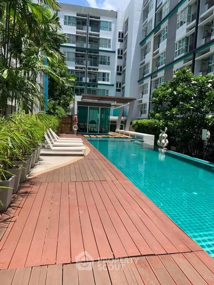 Luxurious condominium pool area with modern design and lush greenery, perfect for relaxation and leisure.