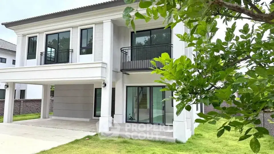 Modern two-story house with large windows and lush green lawn, perfect for family living.