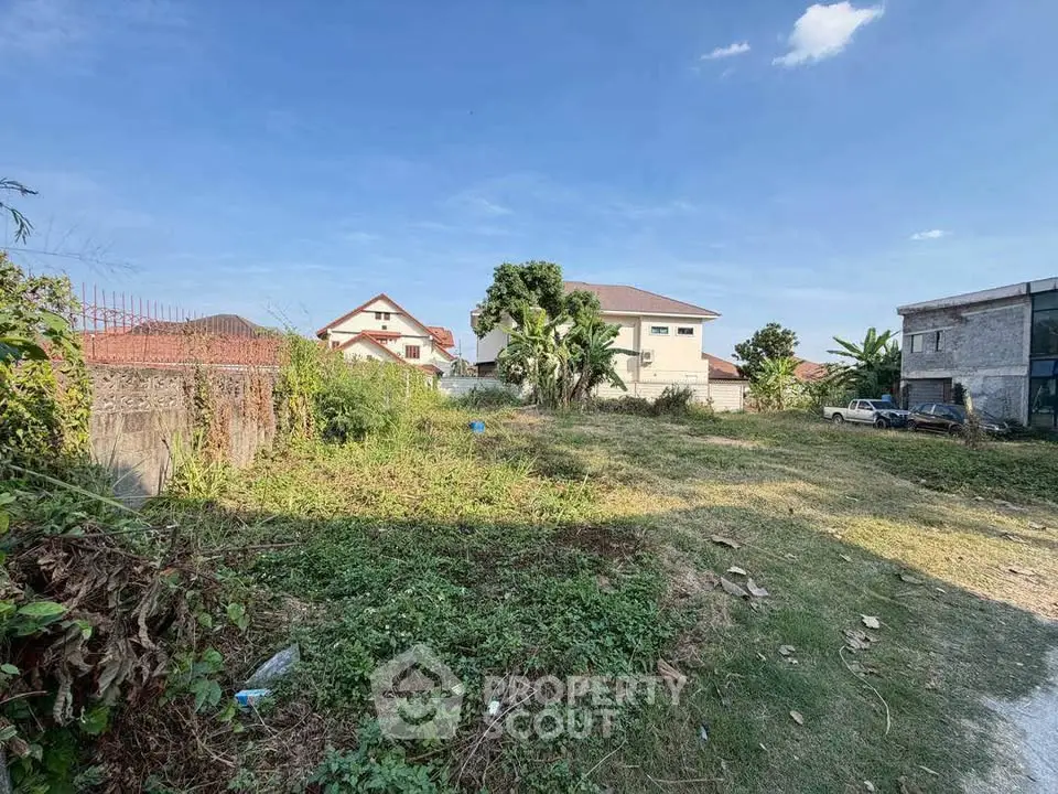 Spacious residential land plot with lush greenery and clear blue sky, ideal for building your dream home.
