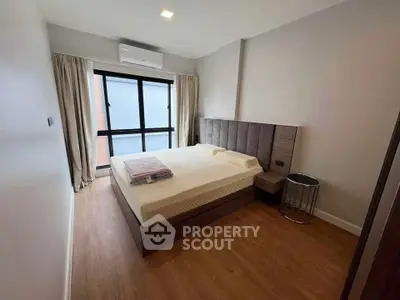 Modern bedroom with sleek design and large window, featuring a comfortable bed and stylish decor.