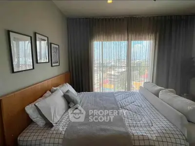 Spacious bedroom with modern decor and large window offering a city view.