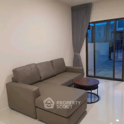Modern living room with sleek gray sofa and large window offering natural light.