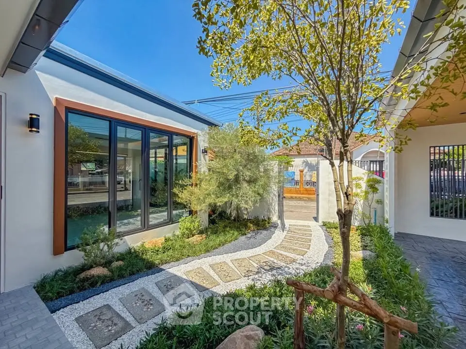 Charming modern home exterior with lush garden and stone pathway, perfect for serene living.