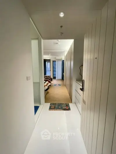 Modern apartment hallway leading to a cozy bedroom with stylish decor and ample natural light.
