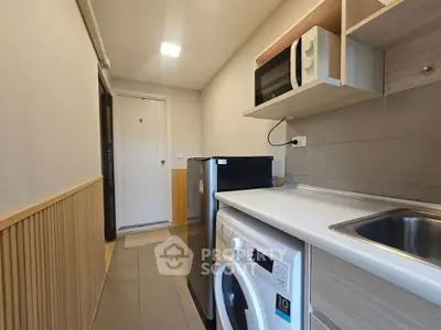 Compact kitchen with modern appliances and washing machine in cozy apartment.