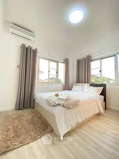 Bright and cozy bedroom with modern decor and large windows for natural light.