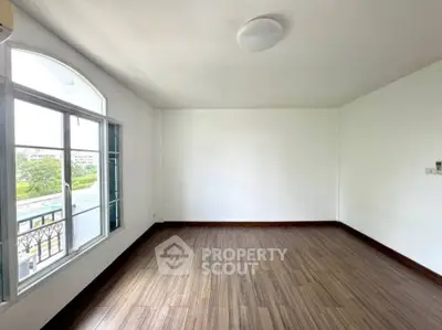 Spacious empty room with large window and wooden flooring, perfect for customization.