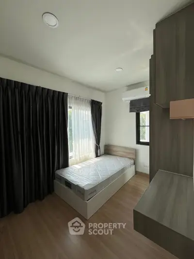 Modern bedroom with natural light, wooden flooring, and sleek furniture design.
