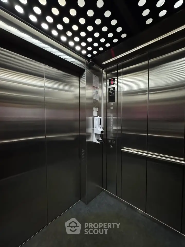 Modern stainless steel elevator interior with sleek design and bright lighting.