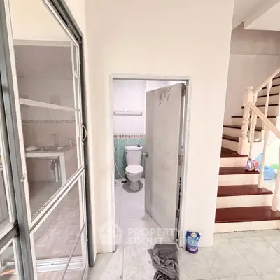Spacious bathroom with modern fixtures next to a staircase in a bright home.