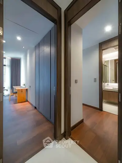 Modern interior with wooden flooring and sleek design, featuring a study area and bathroom entrance.