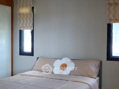 Cozy bedroom with neutral tones and floral accent pillow, perfect for relaxation.