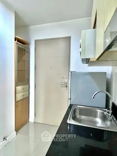 Compact kitchen with sleek cabinetry and modern appliances in a cozy apartment.