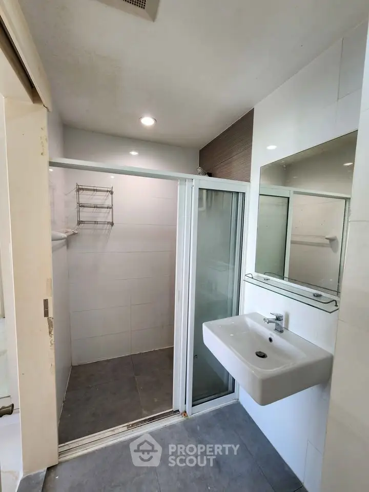 Modern bathroom with sleek shower and wall-mounted sink in a minimalist design.