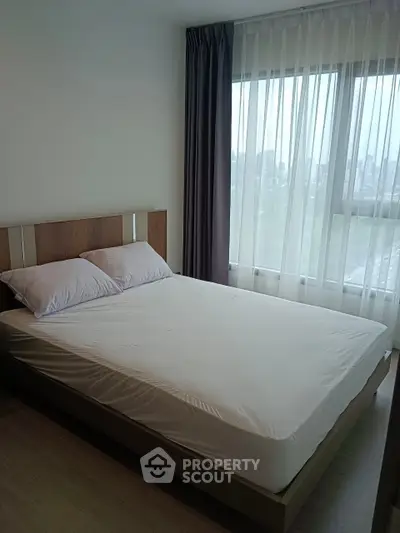 Modern bedroom with large window and city view, featuring a comfortable bed and elegant curtains.