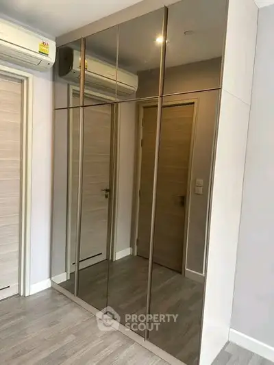 Modern bedroom with mirrored wardrobe and sleek air conditioning unit.