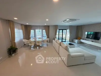 Spacious modern living room with elegant white furniture and large windows.