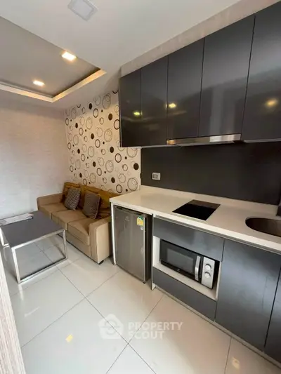 Modern compact kitchen with sleek cabinets and cozy living area in stylish apartment.