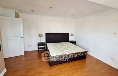 Spacious bedroom with wooden flooring and elegant bed frame in modern apartment.