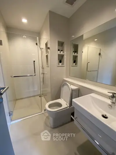 Modern bathroom with glass shower and sleek fixtures in a contemporary home.