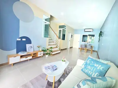 Modern living room with stylish decor and open layout, featuring a cozy sofa and elegant staircase.