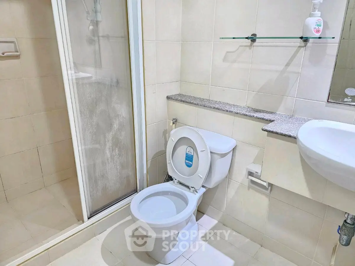 Modern bathroom with shower and toilet in a sleek, tiled design