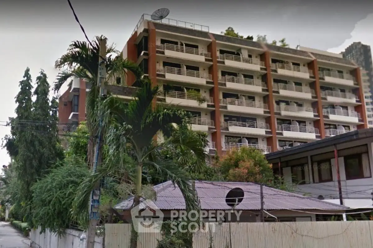 Modern apartment building with lush greenery and balconies in urban setting.