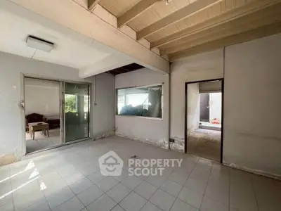 Spacious room with sliding glass doors and tiled flooring, ideal for renovation.