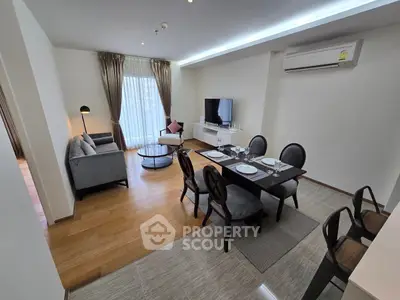 Modern living room with dining area, featuring sleek furniture and natural light.