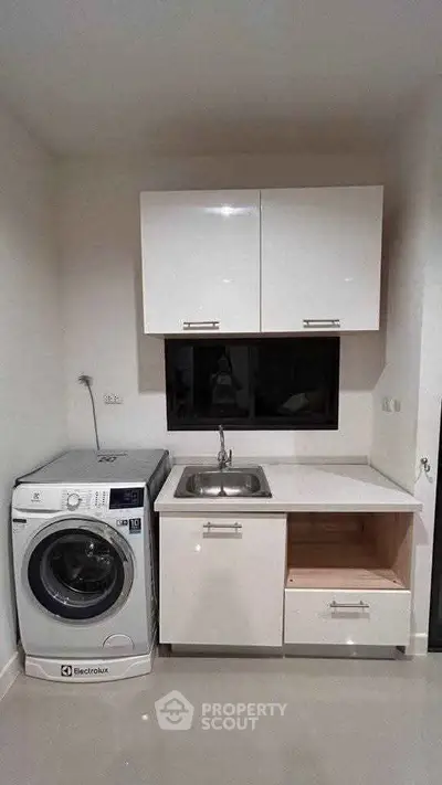 Compact kitchen with washing machine and sleek white cabinets