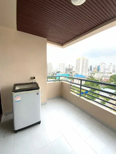 Spacious balcony with city view and washing machine in urban apartment.