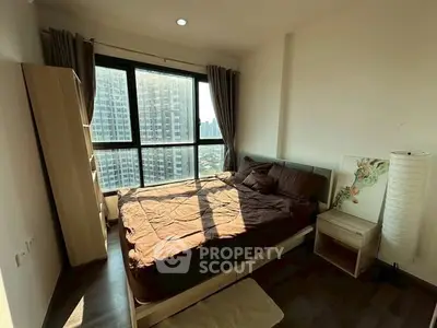 Cozy bedroom with large window offering city view in modern apartment